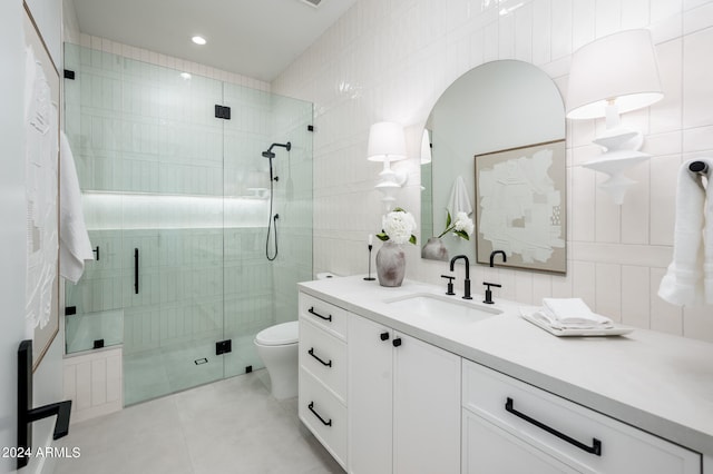 bathroom featuring tile walls, tile patterned flooring, a shower with door, vanity, and toilet