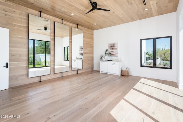 spare room with light wood-type flooring, wood walls, ceiling fan, and wooden ceiling