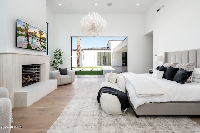 bedroom with a notable chandelier, a high ceiling, and light hardwood / wood-style floors