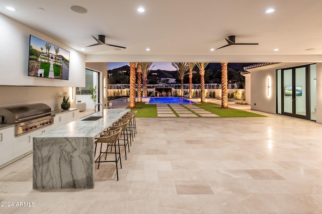 view of patio / terrace featuring an outdoor kitchen, grilling area, an outdoor wet bar, ceiling fan, and a swimming pool