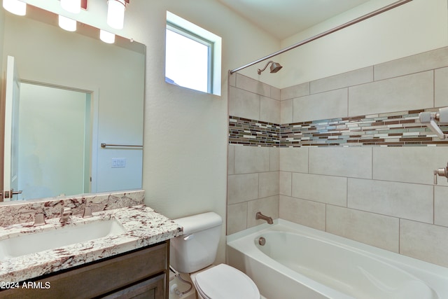 full bathroom featuring tiled shower / bath, vanity, and toilet