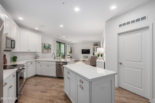 2511 W Queen Creek Rd Unit 174, Chandler, AZ 85248 - kitchen featuring appliances with stainless steel finishes, a sink, a kitchen island, light wood finished floors, and recessed lighting