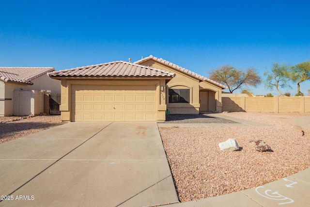 mediterranean / spanish home with fence, driveway, stucco siding, a garage, and a tiled roof