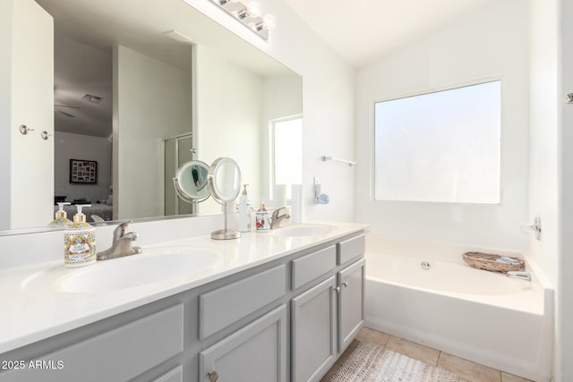 ensuite bathroom with a sink, connected bathroom, double vanity, and tile patterned flooring