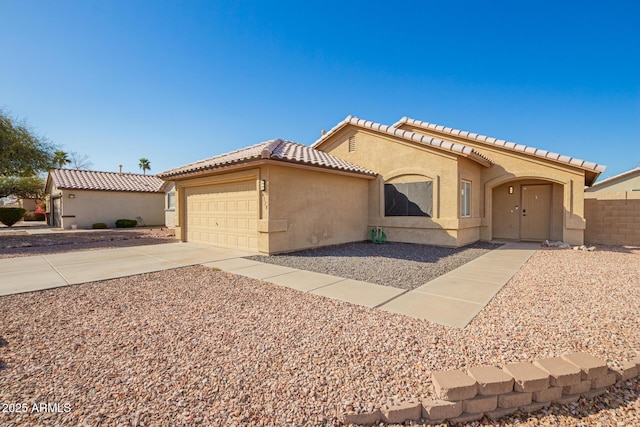 mediterranean / spanish-style house with stucco siding, driveway, fence, a garage, and a tiled roof