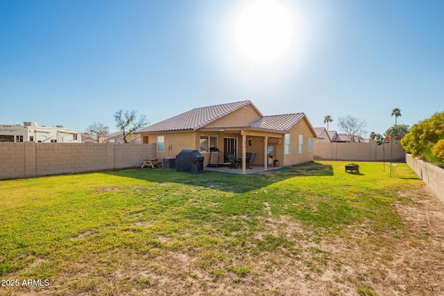 back of house featuring a tile roof, stucco siding, a lawn, a fenced backyard, and a patio