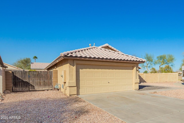 view of property exterior featuring fence, a tiled roof, concrete driveway, stucco siding, and an attached garage