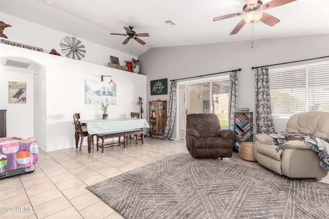 living area featuring light tile patterned floors, a ceiling fan, visible vents, arched walkways, and vaulted ceiling