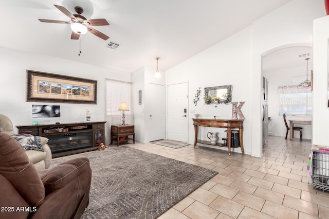 living area featuring visible vents, ceiling fan, lofted ceiling, light tile patterned flooring, and arched walkways