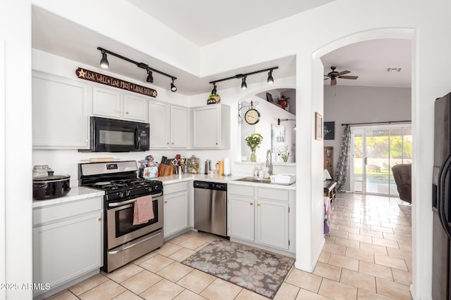 kitchen featuring a ceiling fan, arched walkways, a sink, black appliances, and light countertops