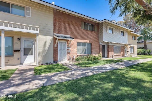 multi unit property featuring a front yard and brick siding