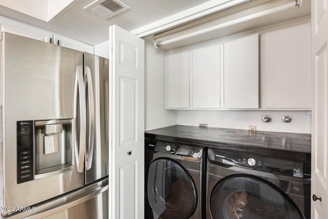 clothes washing area featuring cabinets and washing machine and clothes dryer