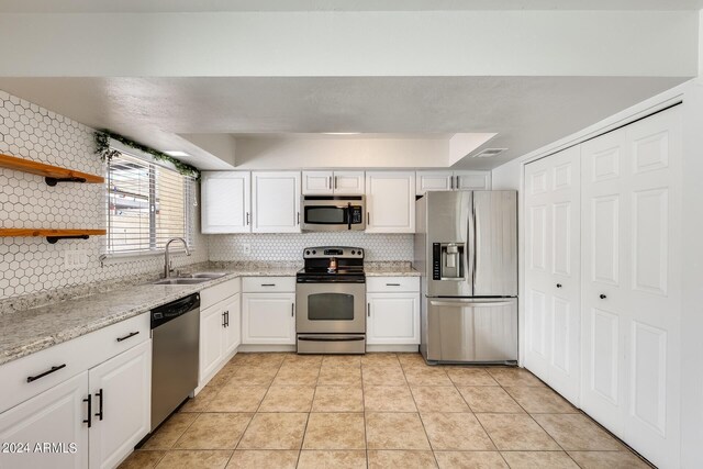 kitchen featuring white cabinetry, tasteful backsplash, light tile patterned floors, stainless steel appliances, and sink