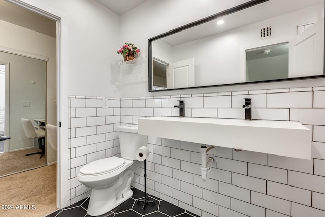 bathroom with tile walls, toilet, and tile patterned flooring