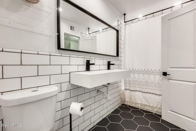 bathroom featuring tile patterned floors, toilet, sink, tile walls, and a shower with curtain