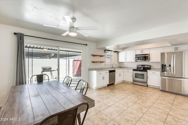 kitchen featuring light tile patterned floors, stainless steel appliances, a sink, white cabinets, and decorative backsplash