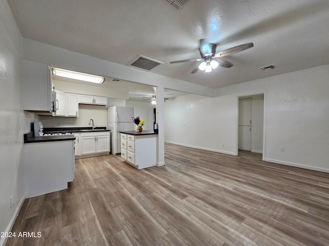 kitchen featuring sink, light wood-type flooring, white cabinetry, ceiling fan, and white refrigerator