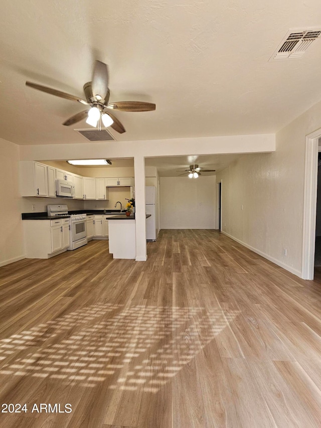 unfurnished living room with sink, light wood-type flooring, and ceiling fan