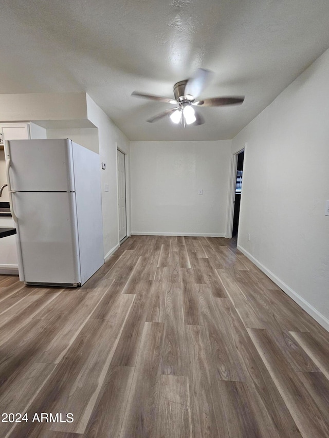 interior space with light hardwood / wood-style flooring, a textured ceiling, and ceiling fan