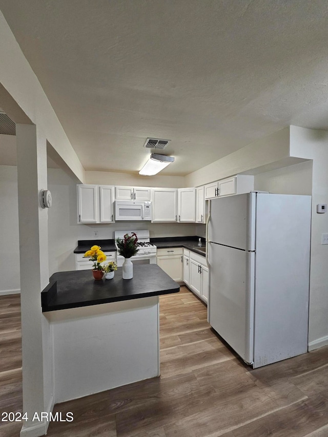 kitchen with white appliances, light wood-type flooring, white cabinetry, and kitchen peninsula