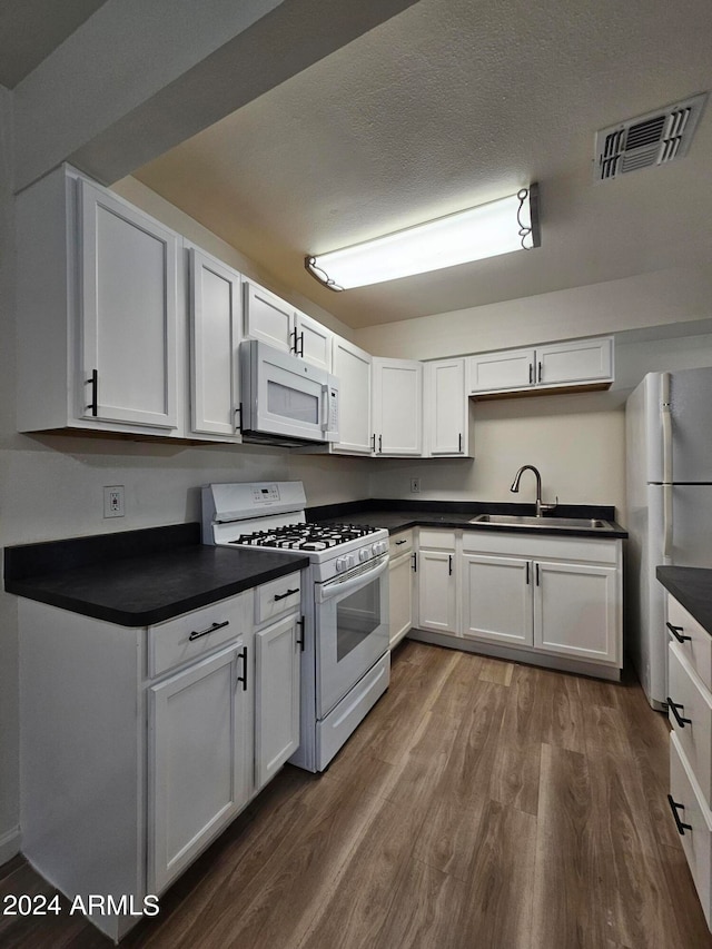 kitchen with white cabinets, sink, wood-type flooring, and white appliances