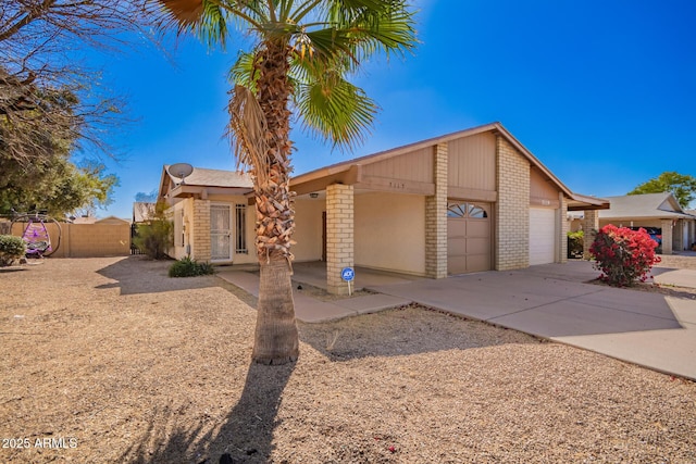 mid-century modern home featuring a garage, concrete driveway, brick siding, and fence