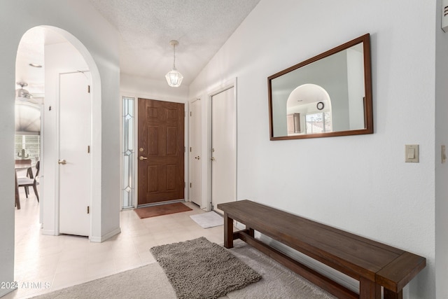 tiled foyer entrance featuring lofted ceiling, a healthy amount of sunlight, and a textured ceiling