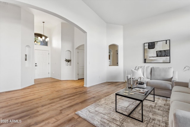 living room with a chandelier, wood-type flooring, and a high ceiling