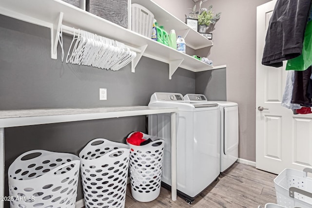 washroom featuring laundry area, baseboards, light wood-style floors, and independent washer and dryer