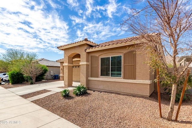 mediterranean / spanish home featuring a garage, concrete driveway, a tiled roof, and stucco siding