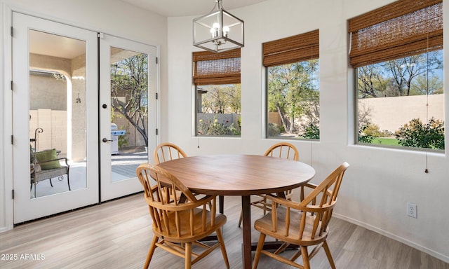 dining area featuring french doors, light wood-type flooring, and a notable chandelier