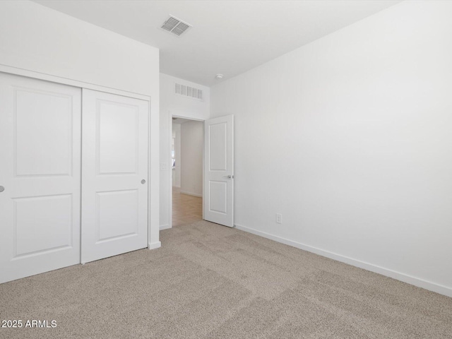 unfurnished bedroom with carpet flooring, baseboards, visible vents, and a closet