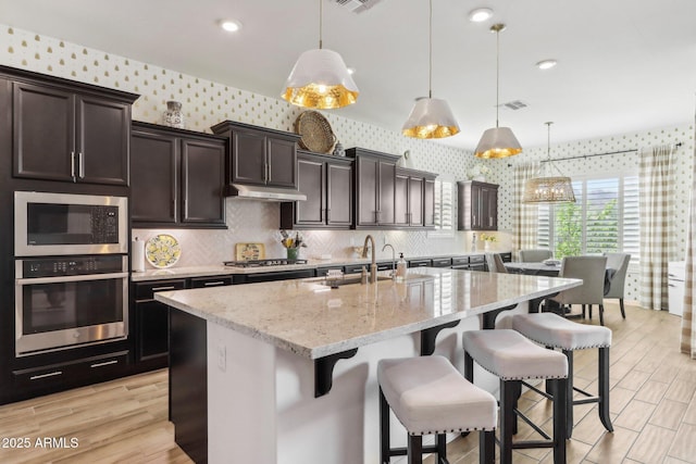 14204 S 179th Ln, Goodyear, AZ 85338 - kitchen featuring under cabinet range hood, a sink, wallpapered walls, and appliances with stainless steel finishes