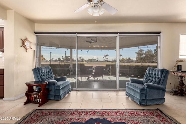 living area with light tile patterned floors, plenty of natural light, baseboards, and ceiling fan