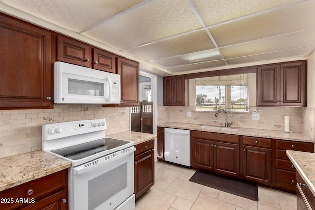 kitchen with tasteful backsplash, light tile patterned flooring, a sink, white appliances, and a drop ceiling