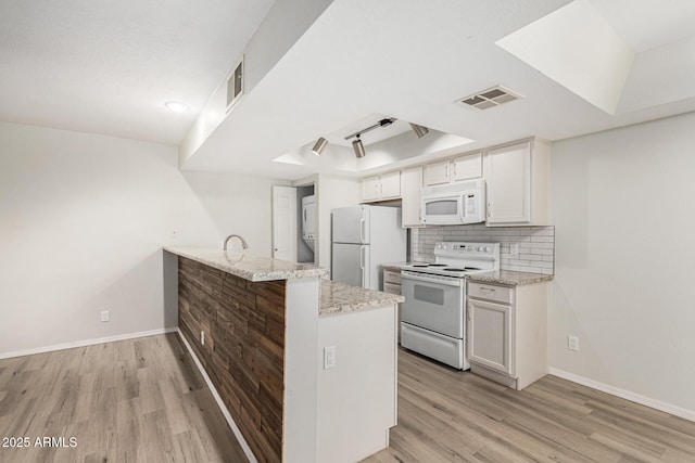 234 N 75th St Unit 209, Mesa, AZ 85207 - kitchen with white appliances, light wood finished floors, a peninsula, and baseboards