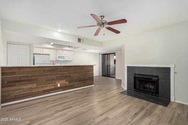 234 N 75th St Unit 209, Mesa, AZ 85207 - unfurnished living room with light wood-type flooring, ceiling fan, a tile fireplace, and baseboards