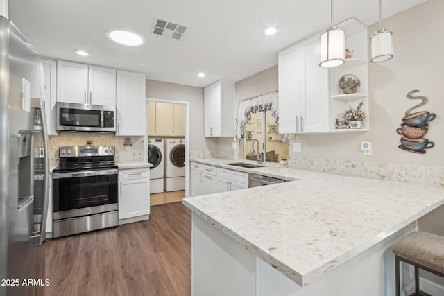 kitchen featuring white cabinets, sink, appliances with stainless steel finishes, kitchen peninsula, and washing machine and clothes dryer