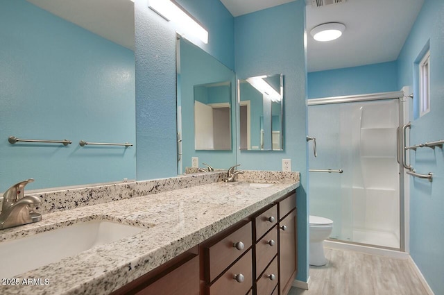 bathroom featuring vanity, hardwood / wood-style flooring, a shower with door, and toilet