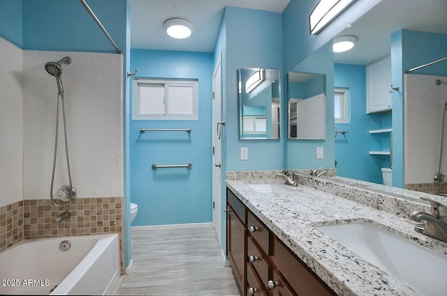 full bathroom featuring tiled shower / bath combo, vanity, wood-type flooring, and toilet