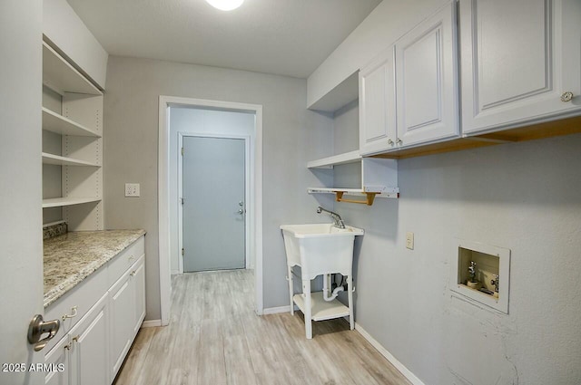 clothes washing area with cabinets, washer hookup, and light hardwood / wood-style floors