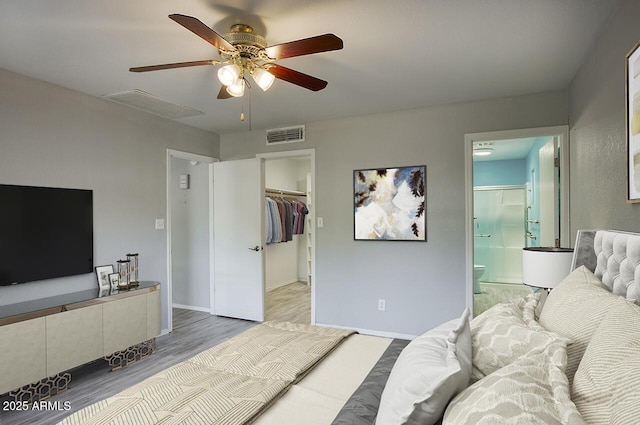 bedroom with ensuite bath, a spacious closet, a closet, ceiling fan, and light hardwood / wood-style floors