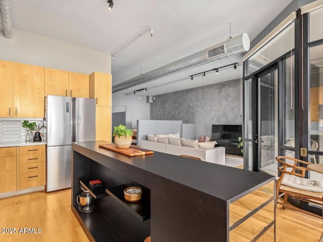 kitchen featuring light hardwood / wood-style floors, stainless steel fridge, and light brown cabinetry