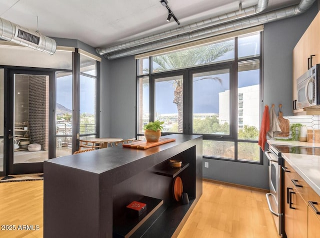 kitchen featuring appliances with stainless steel finishes, light hardwood / wood-style flooring, track lighting, and a kitchen island