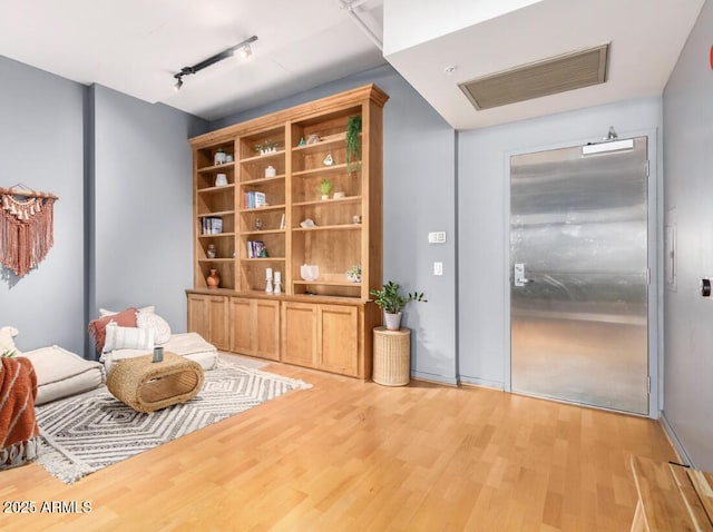 living area featuring track lighting and light hardwood / wood-style floors