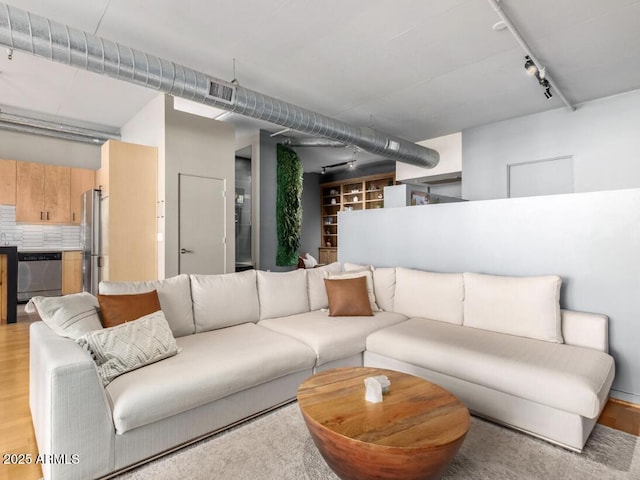 living room featuring rail lighting and light hardwood / wood-style flooring