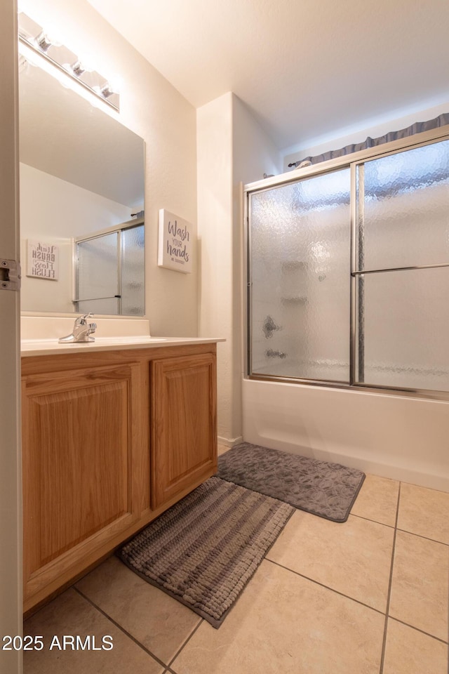 bathroom featuring tile patterned flooring, vanity, and enclosed tub / shower combo