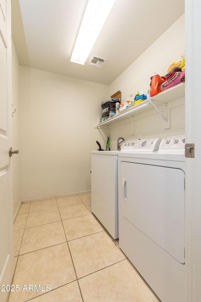 laundry area with separate washer and dryer and light tile patterned floors