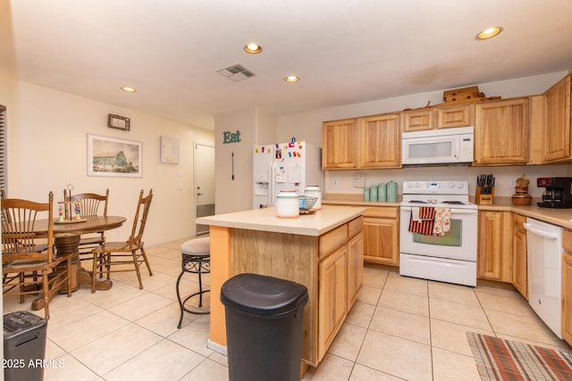 kitchen with light tile patterned flooring, white appliances, a center island, and a breakfast bar area