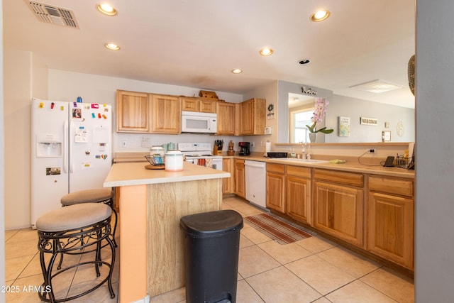 kitchen featuring sink, light tile patterned floors, a kitchen breakfast bar, a kitchen island, and white appliances